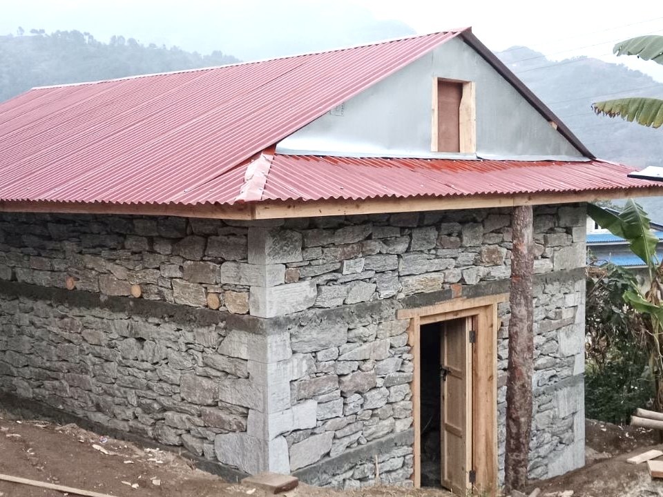 A new stone house with a red corrugated roof